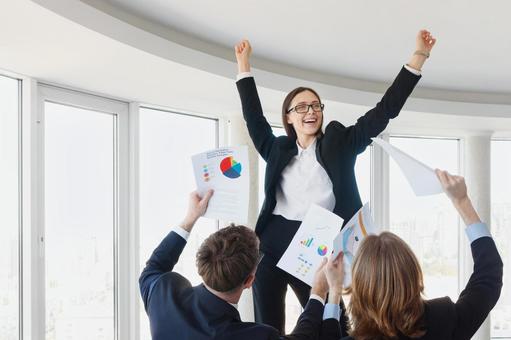 男性たちの前で喜ぶメガネの女性の写真