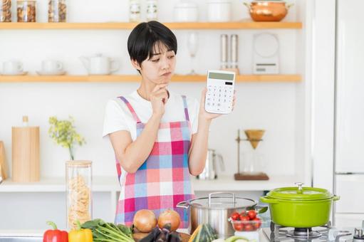電卓を持って悩む主婦。 電卓を持って悩む主婦。の写真