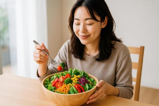 てんこ盛りサラダと女性のランチタイムの写真