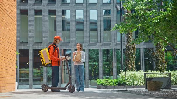 ビルの前でフードデリバリーの受け取りをする女性 配達,フードデリバリー,デリバリーの写真素材