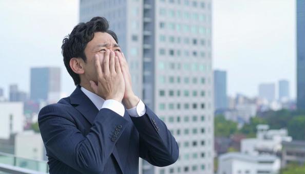 オフィスビルの屋上で苦悩するビジネスマンの写真