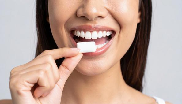 デンタルケアでガムを口にする女性の写真