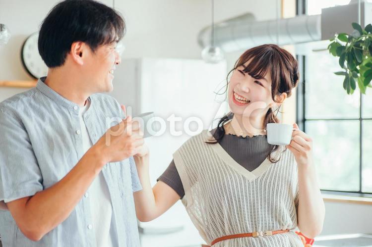 キッチンの前でコーヒーを飲む男女（夫婦） 夫婦,新婚,お茶の写真素材