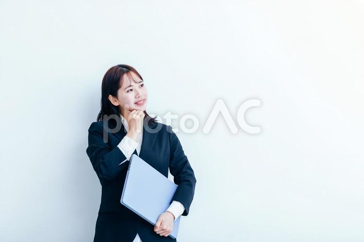 ノートパソコンを抱えるスーツの女性 女性,スーツ,白背景の写真素材