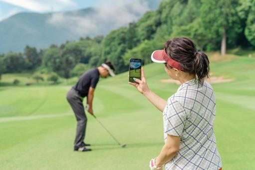 スマホでスイングの確認をするゴルファー スマホでスイングの確認をするゴルファー ゴルフ,スイングチェック,動画の写真素材