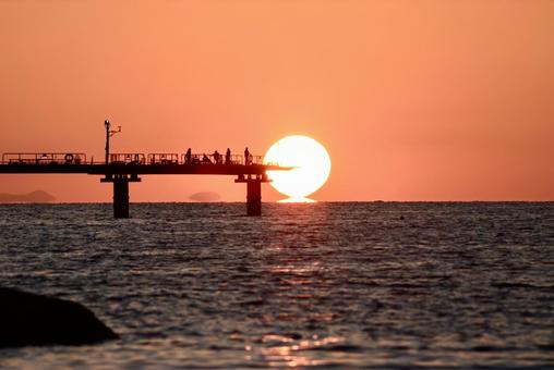 海の桟橋の先に沈むダルマ夕日 海の桟橋の先に沈むダルマ夕日の写真