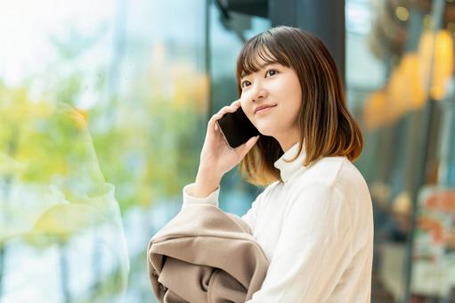 窓の外を見ながらスマホで話す女性 女性,人物,秋の写真素材