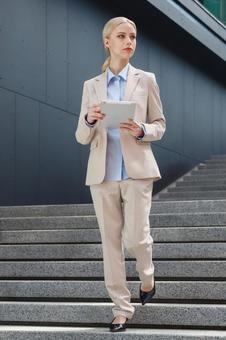 オフィスビルの外でタブレットを持って階段を降りているビジネスウーマン ビジネスウーマン,ビジネス,女性の写真素材