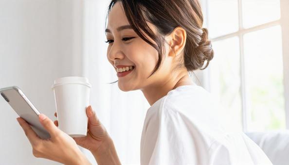 スマホを見ながらドリンクを楽しむ女性 スマホを見ながらドリンクを楽しむ女性の写真