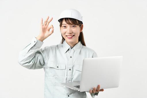 作業服の女性がPCを持ちOKサインをする 作業服の女性がPCを持ちOKサインをする 作業員,女性作業員,建設建設現場の写真素材