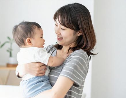 赤ちゃんを抱いて微笑んでいる若いお母さん 赤ちゃんを抱いて微笑んでいる若いお母さんの写真