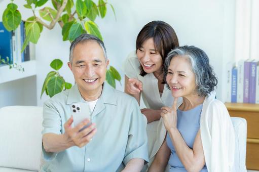 リビングでスマホを見るシニア夫婦と子供 シニア,夫婦,スマホの写真素材