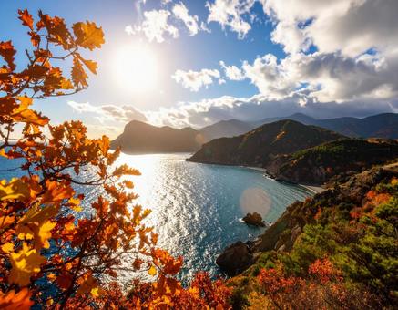 空と太陽、そして海と紅葉している山々 空と太陽、そして海と紅葉している山々の写真