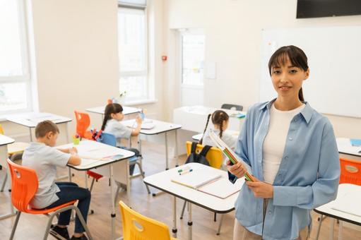 カメラ目線の女性と後ろで勉強する生徒たち 女性,女の子,男の子の写真素材