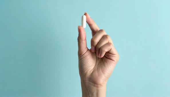 薬一錠を親指と人差し指で持つ手 薬一錠を親指と人差し指で持つ手の写真