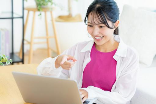 自宅でノートパソコンを操作する若い女性 若い女性,ノートパソコン,笑顔の写真素材