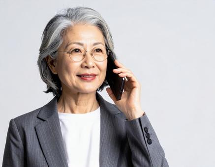 携帯電話で電話する年配のキャリアウーマン 携帯電話で電話する年配のキャリアウーマンの写真