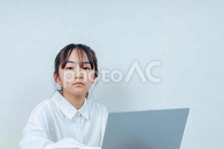 白いシャツのカメラ目線の女の子とPC 女性,小学生,少女の写真素材