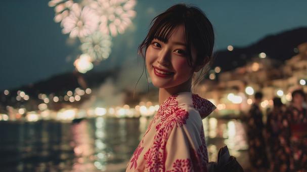 	打ち上げ花火を背景に笑顔の浴衣女性の写真