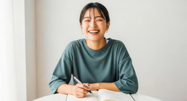 ノートを書きながら笑顔を見せる女性 ノートを書きながら笑顔を見せる女性の写真