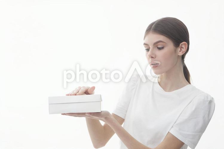 蓋つきの箱を上下で押さえる女性 女性,白,白いの写真素材