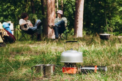 キャンプ用品と2人 ケトル,マグカップ,コンロの写真素材