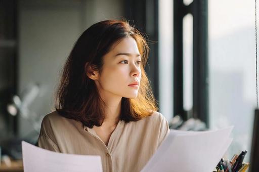 資料を見て悩むビジネス女性 資料を見て悩むビジネス女性の写真
