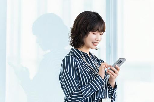 スマホを使う笑顔の女性・ビジネスウーマン スマホを使う笑顔の女性・ビジネスウーマン 女性,スマホ,スマートフォンの写真素材