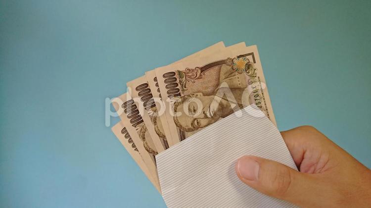 お札の入った封筒を持つ手_青背景 紙幣,お金,一万円札の写真素材