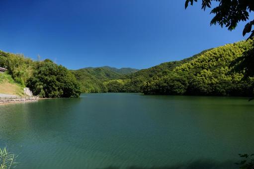 青空の下の山の中のダム湖の写真