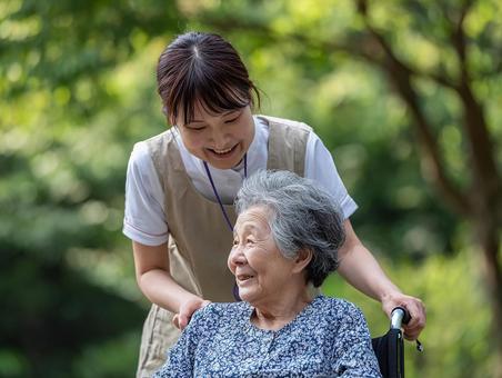 車椅子を押しながら会話する介護士と高齢者 車椅子を押しながら会話する介護士と高齢者の写真