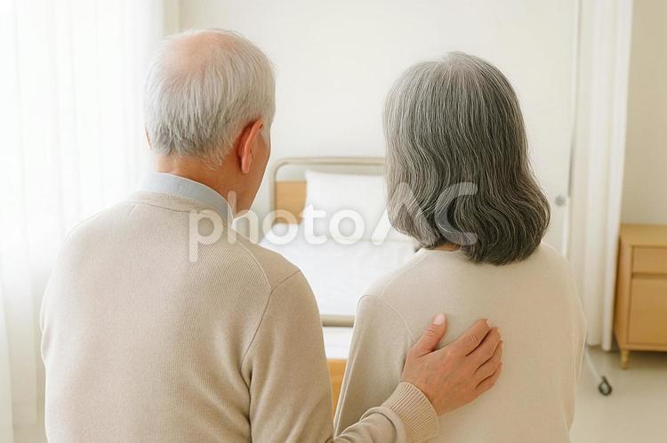 病室のベッドを見つめる老夫婦の後ろ姿 老夫婦,病室,後ろ姿の写真素材