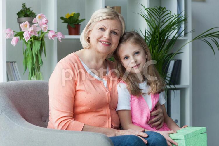 プレゼントボックスを持っておばあちゃんと座る女の子 母の日,おばあちゃん,孫の写真素材
