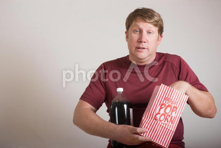 コーラを抱えてポップコーンを食べる外国人男性3 肥満,男性,コーラの写真素材