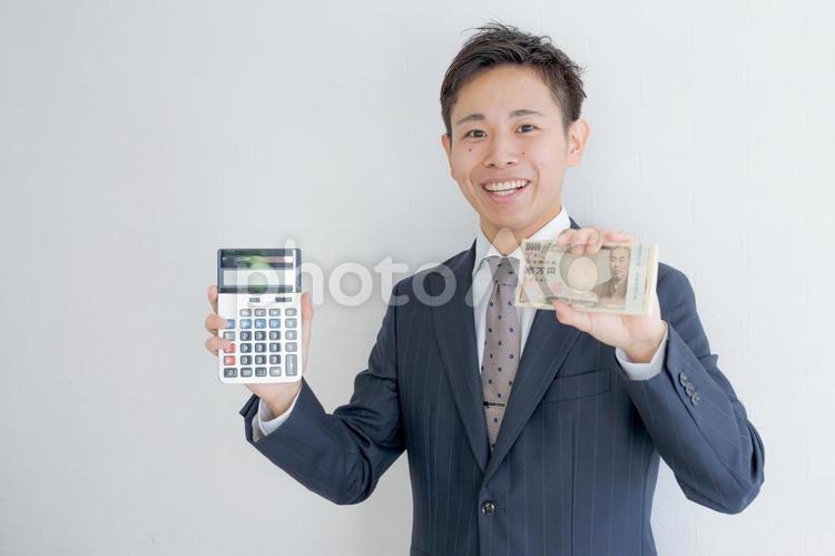 電卓とお金を持つビジネスマン 男性,若い男性,ビジネスマンの写真素材