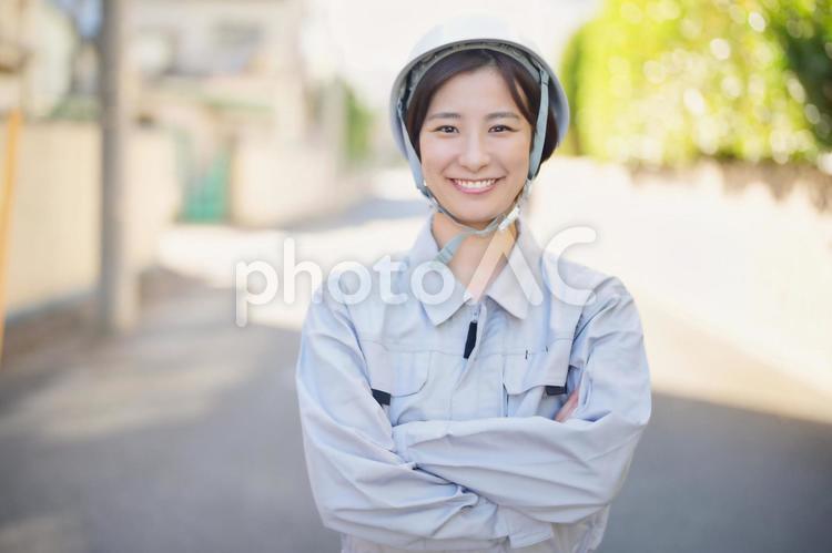 屋外で腕組みをする作業服の女性 女性,日本人,若者の写真素材