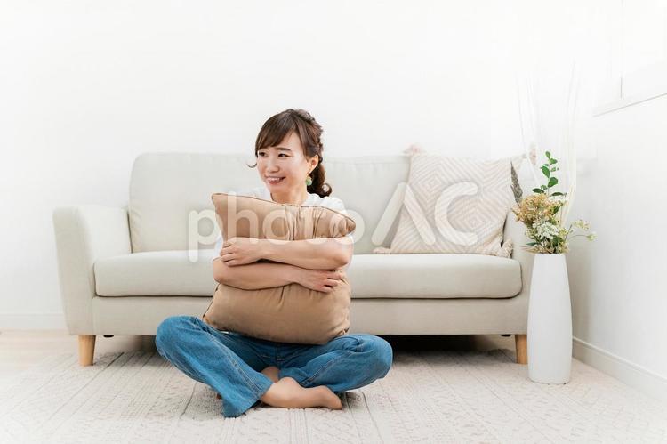 家でクッションを持つ笑顔のアジア人女性 女性,笑顔,笑うの写真素材