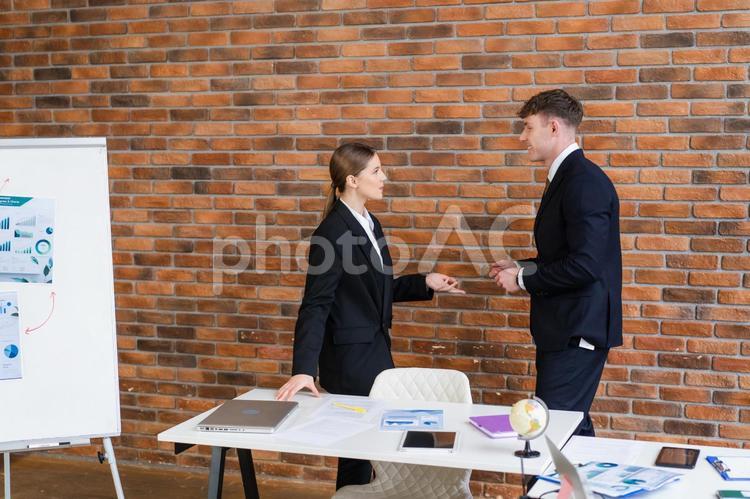 壁際で話す横向きの男女 男女,話す,立ち話の写真素材