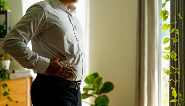 メタボリックなお腹に手を触れる男性 メタボリックなお腹に手を触れる男性の写真