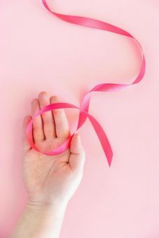 ピンク色のリボンを乗せた女性の手 手,手のみ,手元の写真素材