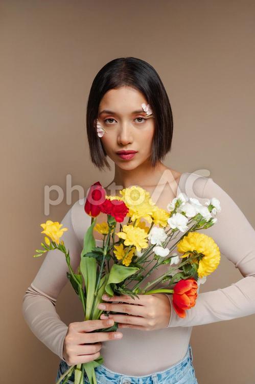 カラフな花の束を持つ正面向きの女性 女性,花束,カラフルの写真素材