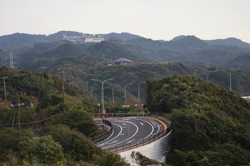 山あいのカーブする道と建物の見える風景 山あい,カーブ,道の写真素材