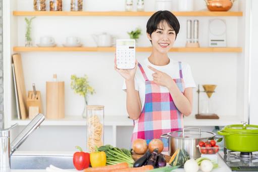 キッチンで電卓を持つ主婦。 キッチンで電卓を持つ主婦。の写真