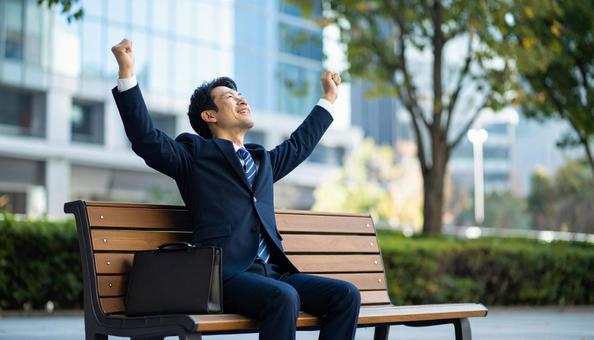 ベンチに座るビジネスマン(ストレッチ中)の写真