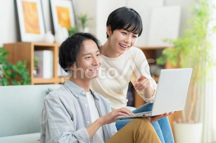 リビングでくつろぐ若い夫婦 カップル,夫婦,パソコンの写真素材