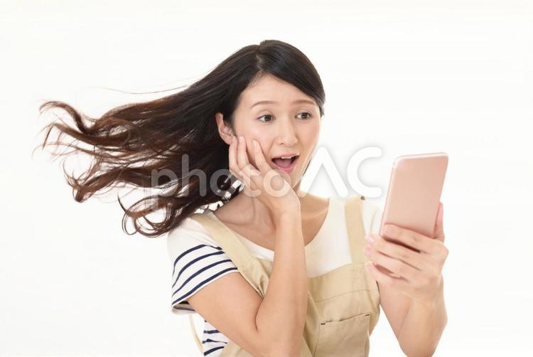 スマートフォンを持つ不安そうな表情の女性 女性,女,主婦の写真素材