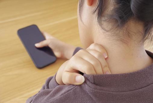 首・肩が痛そうにスマホを操作している女性 スマホ首,ストレートネック,スマホの写真素材
