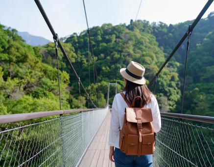 細い吊り橋を渡っていく若い日本人女性 細い吊り橋を渡っていく若い日本人女性の写真
