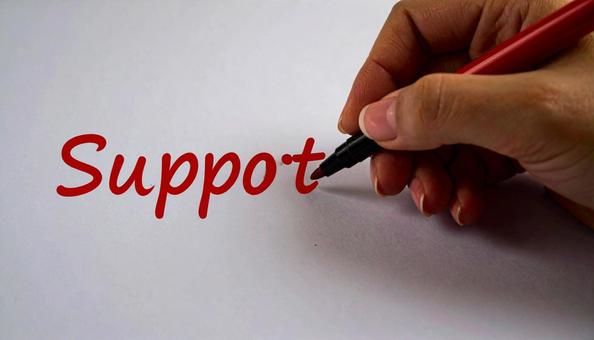 文字「Support」と赤ペンで書く手元の写真