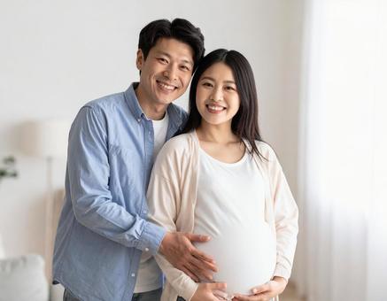 妊娠中の妻と幸せそうに寄り添う夫婦の写真